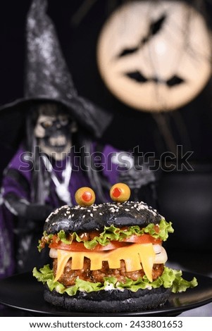 Monster Burger. Black bun, juicy beef cutlet, lettuce, onion, tomato and cheese in the shape of teeth, eyes with olives. Definitely a pick-me-up and a perfect Halloween party appetizer.
