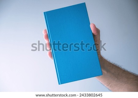Blue hardcover book mockup, man holding book, selective focus