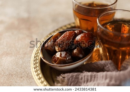 Dates and Hot tea. Traditional Ramadan Kareem concept snack for Iftar or Suhoor meal on warm background. Royalty-Free Stock Photo #2433814381