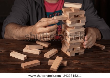 Hand of engineer playing a blocks wood tower game on blueprint or architectural project. Royalty-Free Stock Photo #2433815211