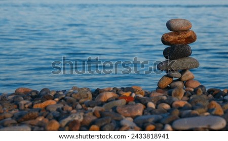 Balance pebble stone in the stoned beach at sunset. Stack of zen stones in harmony and balance with sea view. minimalist view of a perfectly stacked arrangement of pebbles on serene beach