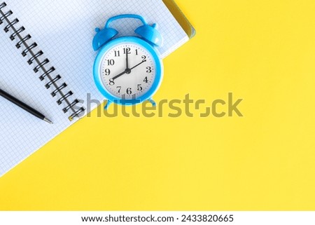 Blue alarm clock and notepad on a yellow background, flat design.