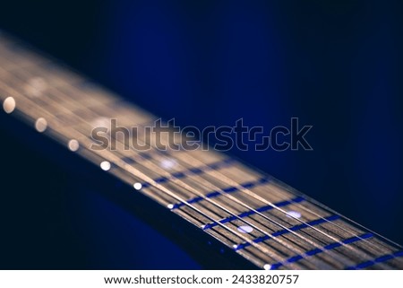Part of an acoustic guitar, guitar fretboard on a black background. Royalty-Free Stock Photo #2433820757