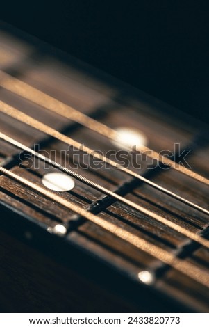 Part of an acoustic guitar, guitar fretboard on a black background. Royalty-Free Stock Photo #2433820773