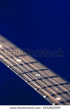 Part of an acoustic guitar, guitar fretboard on a black background. Royalty-Free Stock Photo #2433820909