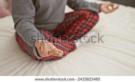 Close-up of unidentifiable person meditating in lotus position on a bed, suggesting tranquility. Royalty-Free Stock Photo #2433825485