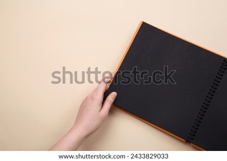 Woman with open photo album at beige background, top view. Space for text