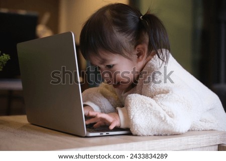 Smart and attractive Asian girl kid looking at the laptop , video call with someone hand using keyboard. Family enjoy distant talk by video call, spend time on internet, online education concept.	
