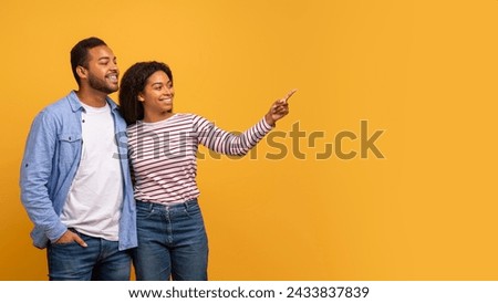 Check This. Happy Black Spouses Pointing Aside At Copy Space With Finger, Smiling African American Man And Woman Standing On Yellow Background, Showing Free Place For Your Advertisement Or Offer Royalty-Free Stock Photo #2433837839