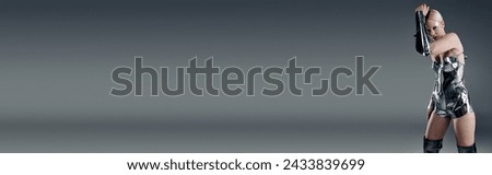 futuristic peculiar woman in metallic attire looking straight at camera on gray backdrop, banner Royalty-Free Stock Photo #2433839699