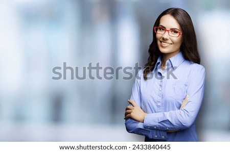 Portrait of cheerfully smiling amazed businesswoman in eye glasses spectacles, indoors. Young business woman account bank manager on blurred office interior background.