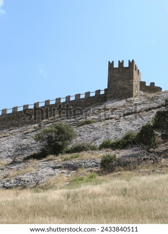 A medieval fortress on a stone rock against the background of a clear blue sky.