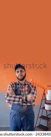 Painter man with crossed arms holding paint roller looking at camera, with natural face and confident expression. Vertical banner