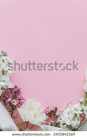 Stylish flowers flat lay on pink background with space for text. Happy womens day and Mothers day. Beautiful tulips and spring flowers border, greeting card template. Floral banner