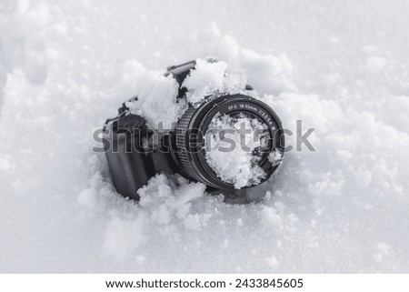 Winter snow camera vintage.Professional digital SLR camera with frosty lens lies in a snowdrift in winter in the snow with copy space