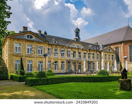 Valkenburg, South Limburg, Netherlands. May 14, 2023. Chateau St. Gerlach, backyard terrace with tables, chairs and closed umbrellas, green grass and bushes, view from a side angle Royalty-Free Stock Photo #2433849201