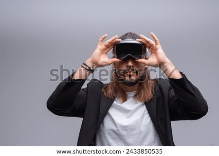 A young man engages with a virtual world using a mixed reality spacial computer headset, symbolizing cutting-edge technology in gaming and immersive digital experiences.  Royalty-Free Stock Photo #2433850535