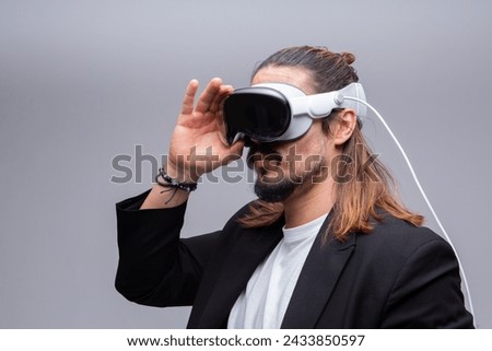 A young man engages with a virtual world using a mixed reality spacial computer headset, symbolizing cutting-edge technology in gaming and immersive digital experiences.  Royalty-Free Stock Photo #2433850597
