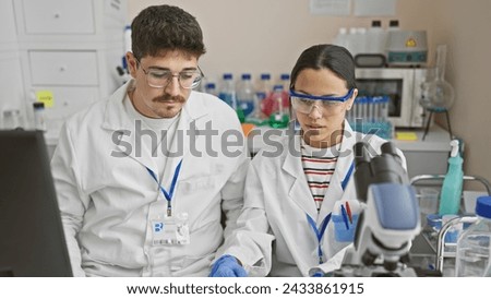 A man and woman in lab coats analyzing samples together in a scientific laboratory.