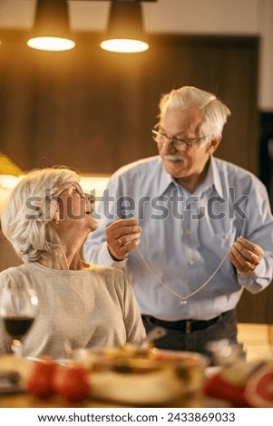 A senior man is giving his wife a necklace on valentines day.