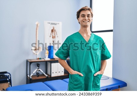Young caucasian man pysiotherapist smiling confident standing at rehab clinic