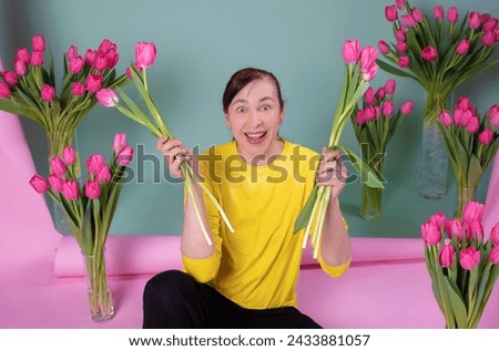 A happy middle-aged woman with a bouquet of tulips is happy and smiling on a pink-green background. Royalty-Free Stock Photo #2433881057