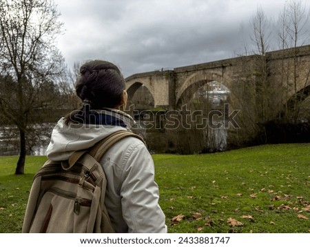 Contemplative Solo Traveler Gazing at Historic Bridge