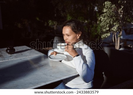 Portrait of a multi ethnic beautiful woman entrepreneur in casual clothes, drinking delicious freshly brewed coffee in the outdoor cafe, enjoying her breakfast and morning vibes before going to work Royalty-Free Stock Photo #2433883579