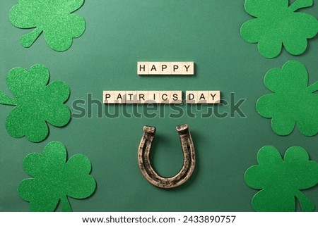 St. Patrick's day frame with clover leaves and horseshoe on green background. View from above. Wooden block with text - Happy Patricks day.