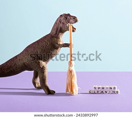 Dinosaur sweeps cubes with the words spring cleaning