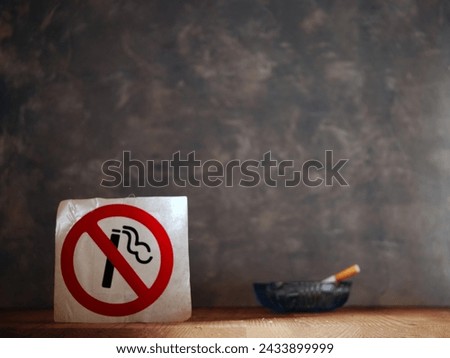 Smoking cigarette in front of no smoking sign wide shot selective focus