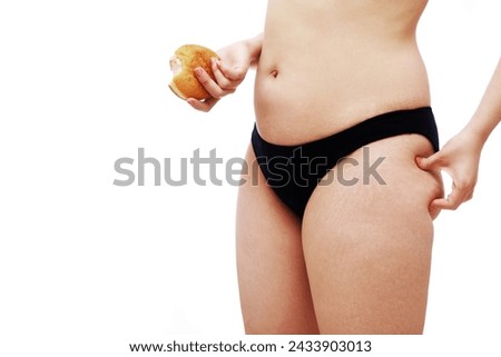 Real female body with stretch marks after childbirth or weight gain. Portrait of overweight enjoing woman eating a donut at. The concept of diet and body positive.