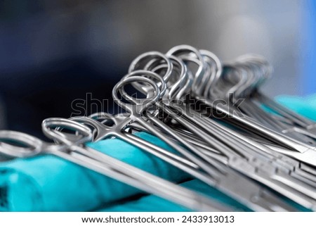 Sterile surgical instruments and tools including scalpels, scissors, forceps and tweezers arranged on a table for a surgery, Sterilized surgical instruments on the blue wrap	 Royalty-Free Stock Photo #2433913013