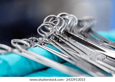 Sterile surgical instruments and tools including scalpels, scissors, forceps and tweezers arranged on a table for a surgery, Sterilized surgical instruments on the blue wrap	 Royalty-Free Stock Photo #2433913015