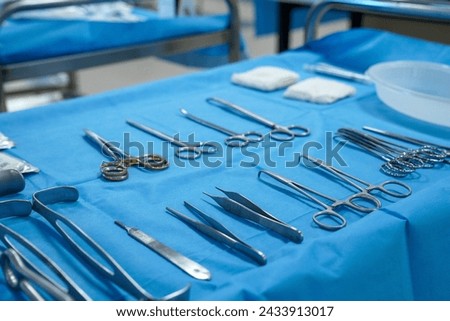 Sterile surgical instruments and tools including scalpels, scissors, forceps and tweezers arranged on a table for a surgery, Sterilized surgical instruments on the blue wrap	 Royalty-Free Stock Photo #2433913017