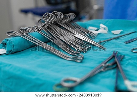 Sterile surgical instruments and tools including scalpels, scissors, forceps and tweezers arranged on a table for a surgery, Sterilized surgical instruments on the blue wrap	 Royalty-Free Stock Photo #2433913019