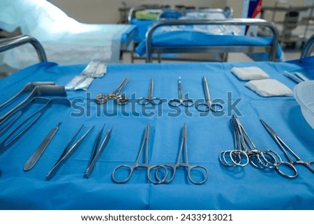 Sterile surgical instruments and tools including scalpels, scissors, forceps and tweezers arranged on a table for a surgery, Sterilized surgical instruments on the blue wrap	 Royalty-Free Stock Photo #2433913021
