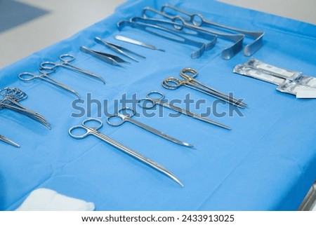 Sterile surgical instruments and tools including scalpels, scissors, forceps and tweezers arranged on a table for a surgery, Sterilized surgical instruments on the blue wrap	 Royalty-Free Stock Photo #2433913025