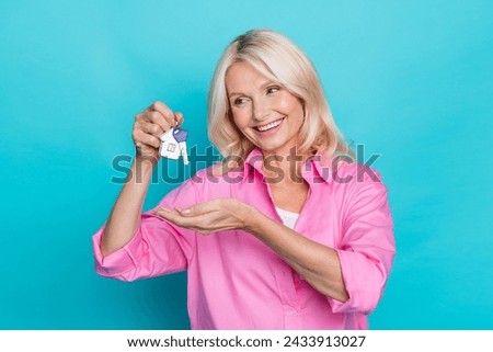 Photo portrait of lovely senior lady hold look keyholder dressed stylish pink smart casual garment isolated on aquamarine color background