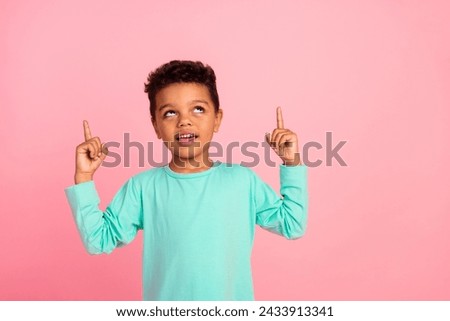 Photo portrait of adorable little boy point look up empty space dressed stylish cyan garment isolated on pink color background