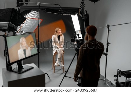 Photographer capturing woman on stool in studio