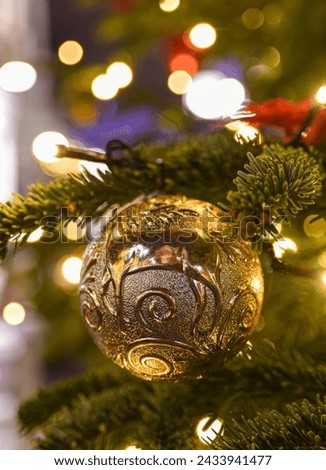 A gold ball on a Christmas tree. Yellow blurred lights in the background. Christmas background.