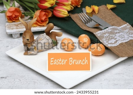 Easter brunch: The text Easter brunch on a place card with cutlery, plates and Easter decorations on a table.