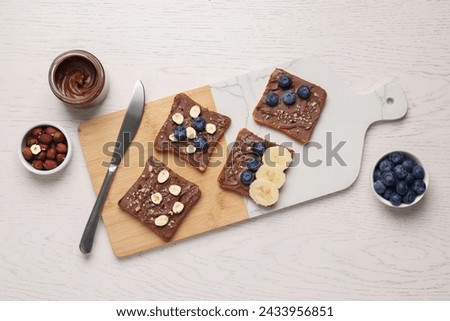 Different tasty toasts with nut butter and products on white wooden table, flat lay