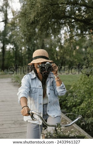 Beautiful woman riding bike with flowers in front basket. She is riding a bicycle and taking pictures of the scenery