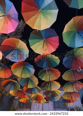 Rainbow coloured umbrellas hanging upside down from the ceiling, making a lovely picture 