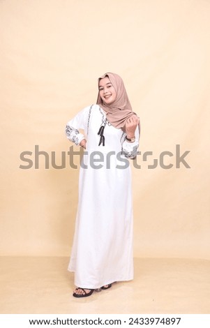 Full body portrait of a beautiful young Asian Muslim woman in a cheerful hijab posing gracefully. for advertising, content, banners and Ramadan Royalty-Free Stock Photo #2433974897