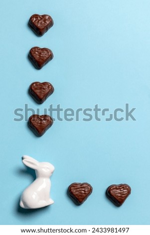 White ceramic  Easter bunny figurine and heart-shaped chocolates on a blue background 