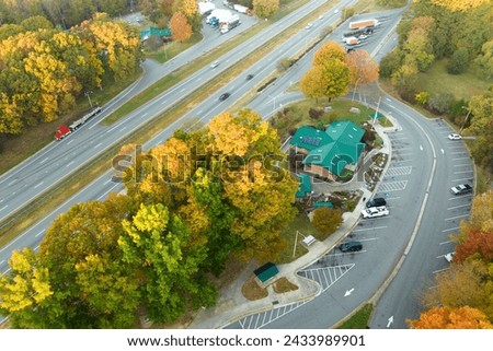 View from above of big parking rest area for cars and trucks near busy american highway with fast moving traffic. Recreational place during interstate travel Royalty-Free Stock Photo #2433989901