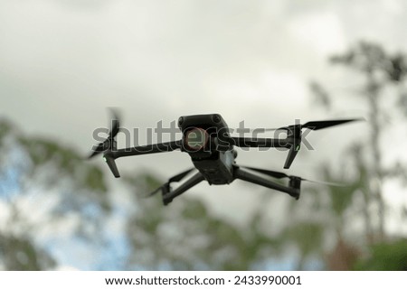 Drone with digital camera and fast rotating propellers flying taking video and pictures